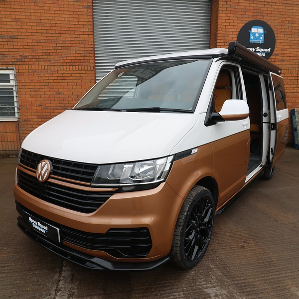 Brown and white van parked in front of a brick building